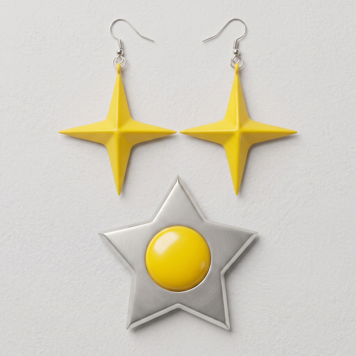 Yellow star drop earrings and silver star pin with yellow center on a light grey textured background