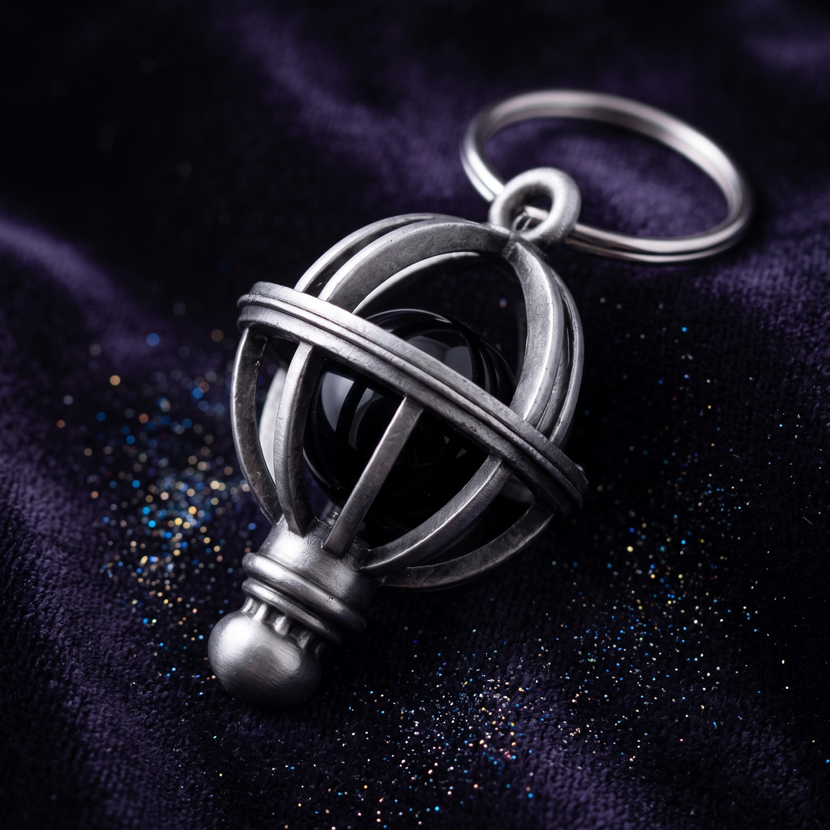 Close-up of the Orion's Belt charm's silver cage and galaxy marble on dark fabric