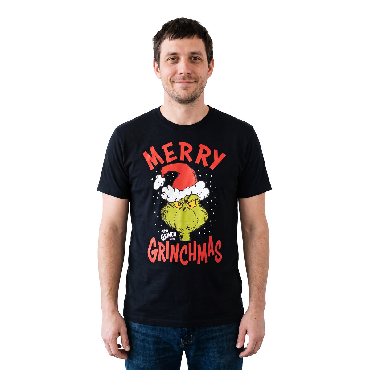 Smiling man wearing the black Merry Grinchmas T-shirt with jeans, front view on white