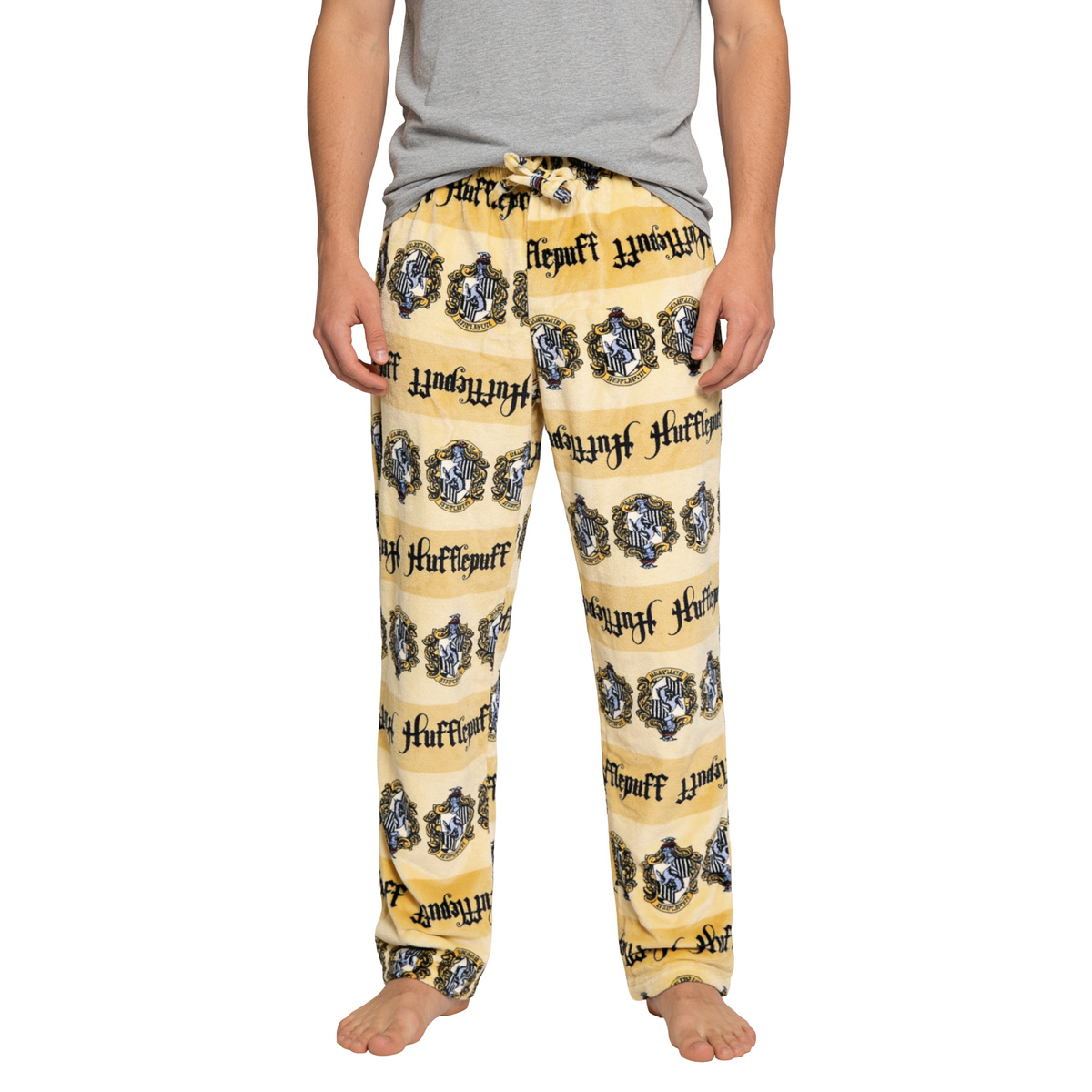 Yellow Harry Potter Hufflepuff plush sleep pants with house crest print, front view worn barefoot
