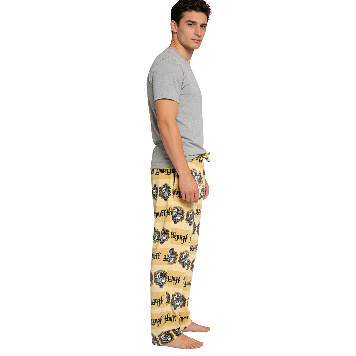 Man in a grey tee wearing the yellow Hufflepuff sleep pants, three-quarter view on white