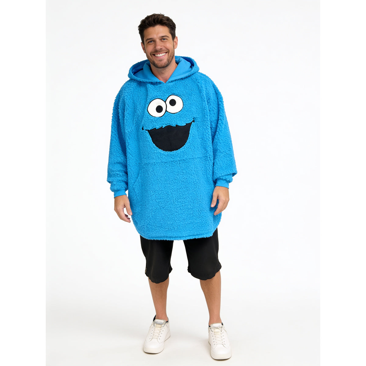 Smiling man wearing the Cookie Monster fleece poncho with shorts, full front view